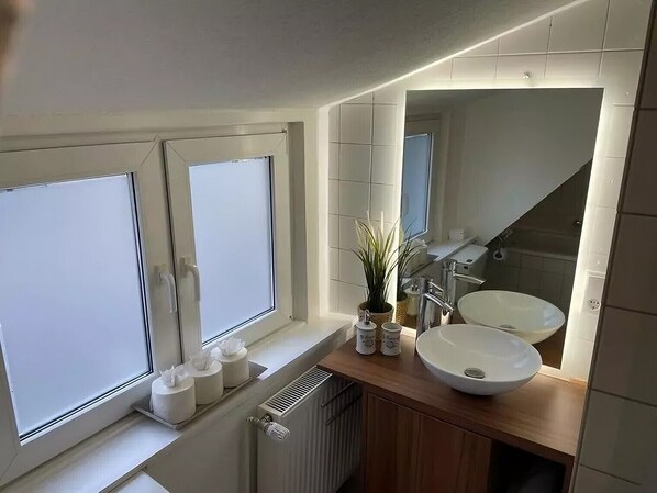 Een moderne badkamer met een groot raam, een wastafel en een spiegel.