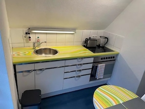 A compact kitchen with a striped countertop, a sink, a toaster, and a stove.