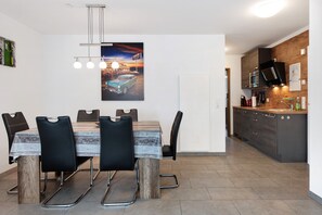 A modern kitchen with a built-in microwave, a wooden dining table with black chairs, and a pendant light fixture. - Holiday Apartment "Todtmoos" with Mountain View, Balcony & Wi-Fi (Todtmoos)