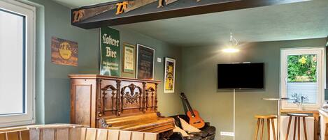 Una sala de estar con un piano, una guitarra, un televisor y una zona de bar.