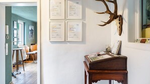 Une pièce avec une table en bois, des certificats encadrés accrochés au mur et une grande décoration en forme de bois de cerf.