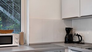 Une cuisine équipée d’un four à micro-ondes, d’une machine à café et d’un panier posé sur le comptoir.