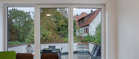 A room with a view of a garden and a building through large windows.