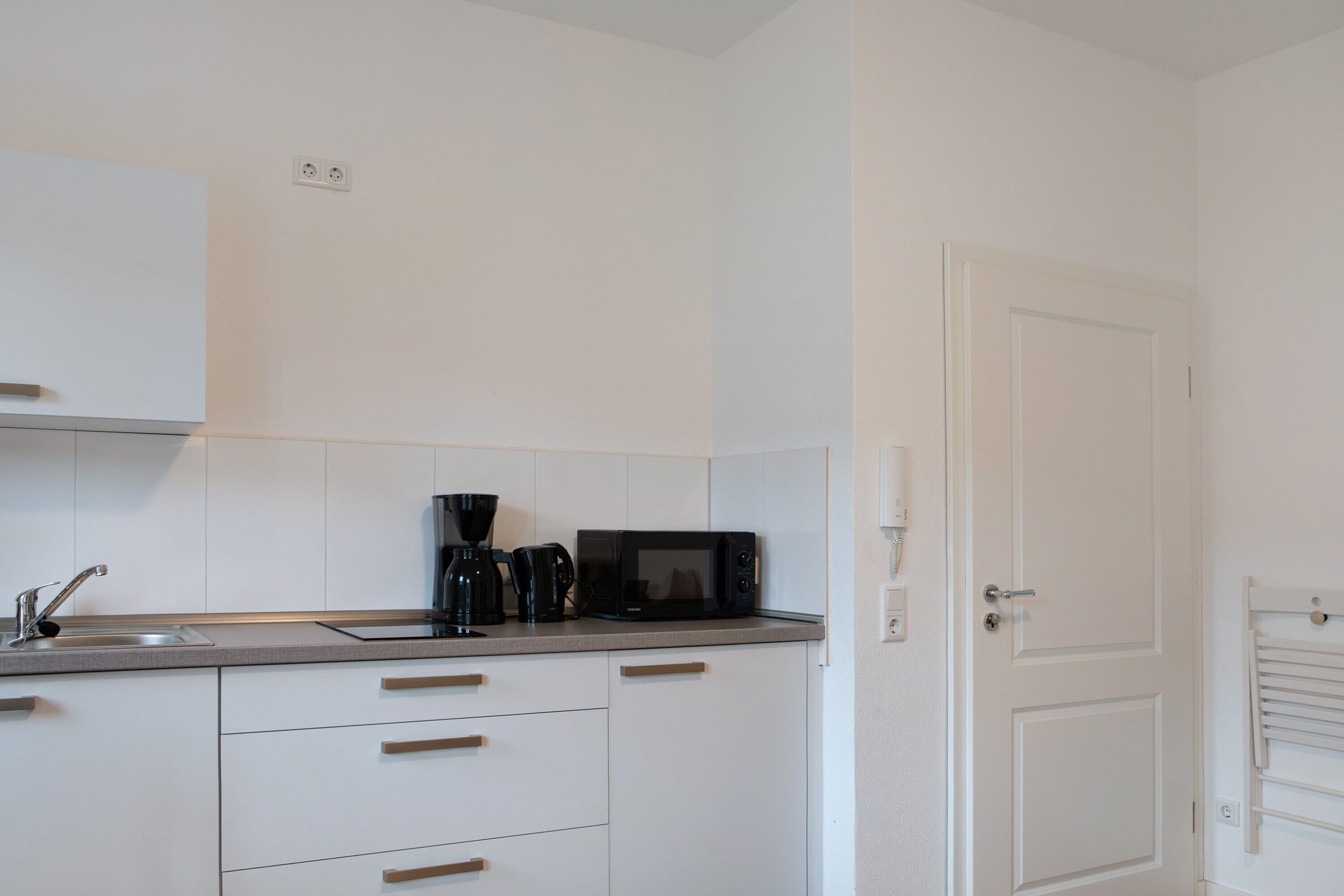A compact kitchen with a microwave, coffee maker, and a sink.