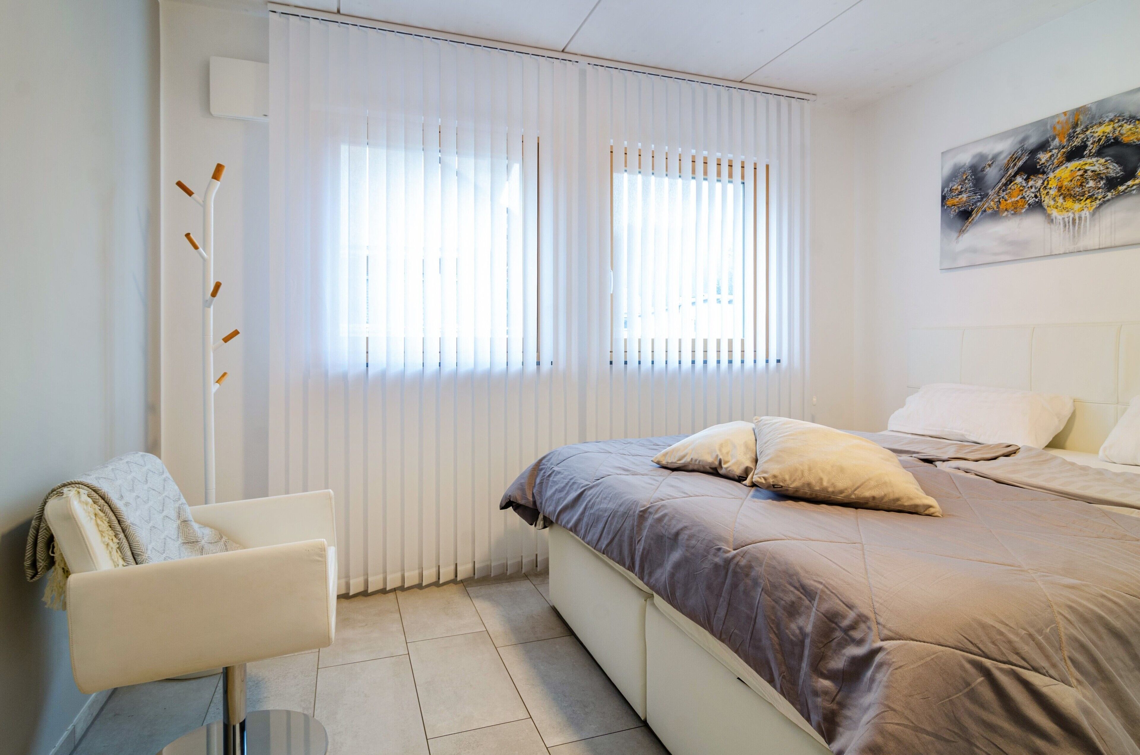 Una camera da letto con un letto, una sedia e una finestra con tende.