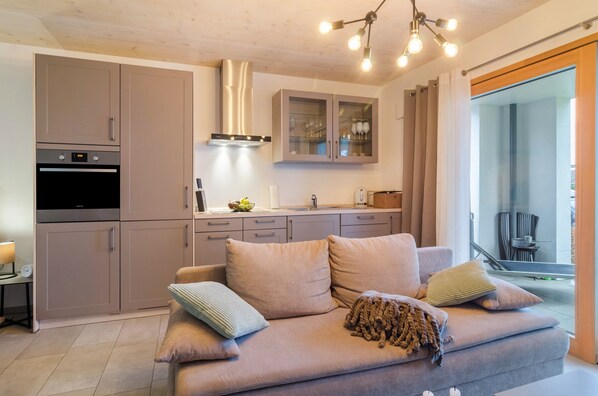A modern kitchen with a built-in oven, a stainless steel range hood, and a dining area with a glass cabinet.