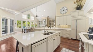 A spacious kitchen with white cabinetry, a large island with a sink, and a clock on the wall. - Updated Seabrook 4Bed with Golf Views, Screened Porch & Club Access! (Seabrook Island)
