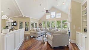 A spacious living room with a high ceiling, large windows, and a wooden floor. - Updated Seabrook 4Bed with Golf Views, Screened Porch & Club Access! (Seabrook Island)