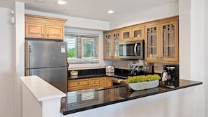 A modern kitchen with stainless steel appliances, wooden cabinets, and a black countertop. - BEACHFRONT! Modern, upgraded villa! East Beach Kiawah! (Kiawah Island)