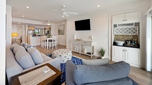 A modern living room with a grey sofa, ottoman, and coffee table. A dining area with a white table and chairs is visible in the background. - BEACHFRONT! Modern, upgraded villa! East Beach Kiawah! (Kiawah Island)
