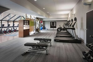 Un gimnasio moderno con cintas de correr, bancos de pesas y pesas sueltas.
