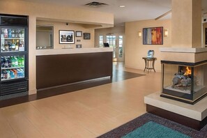 A hotel lobby with a reception desk, a fireplace, and a refrigerator stocked with beverages. - Spacious Accommodation in Charleston! W/ Private Kitchenette! Pets are Welcome! (Charleston)