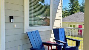 A porch with two Adirondack chairs and a small table. - Cottage by the Trees (Bellingham)