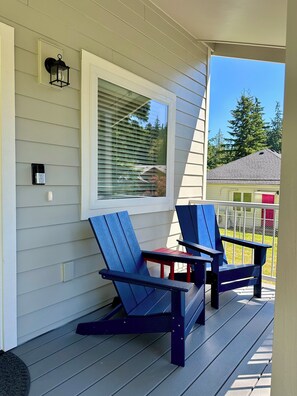 A porch with two Adirondack chairs and a small table.