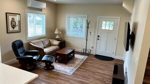 A living room with a sofa, two chairs, a coffee table, and a TV stand. - Cottage by the Trees (Bellingham)