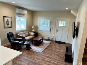 A living room with a sofa, two chairs, a coffee table, and a TV stand.