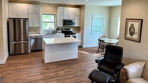 A modern kitchen with white cabinets, stainless steel appliances, and a central island. - Cottage by the Trees (Bellingham)