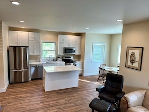 A modern kitchen with white cabinets, stainless steel appliances, and a central island.