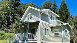 A two-story house with a covered porch and a staircase leading to the upper level. - Cottage by the Trees (Bellingham)