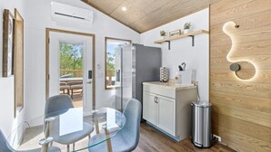 A modern kitchen with a glass dining table, white cabinets, and a wooden ceiling.
