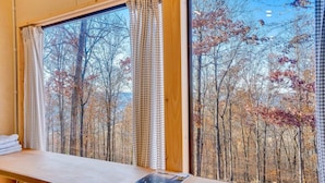 A room with a large window overlooking a forested area.