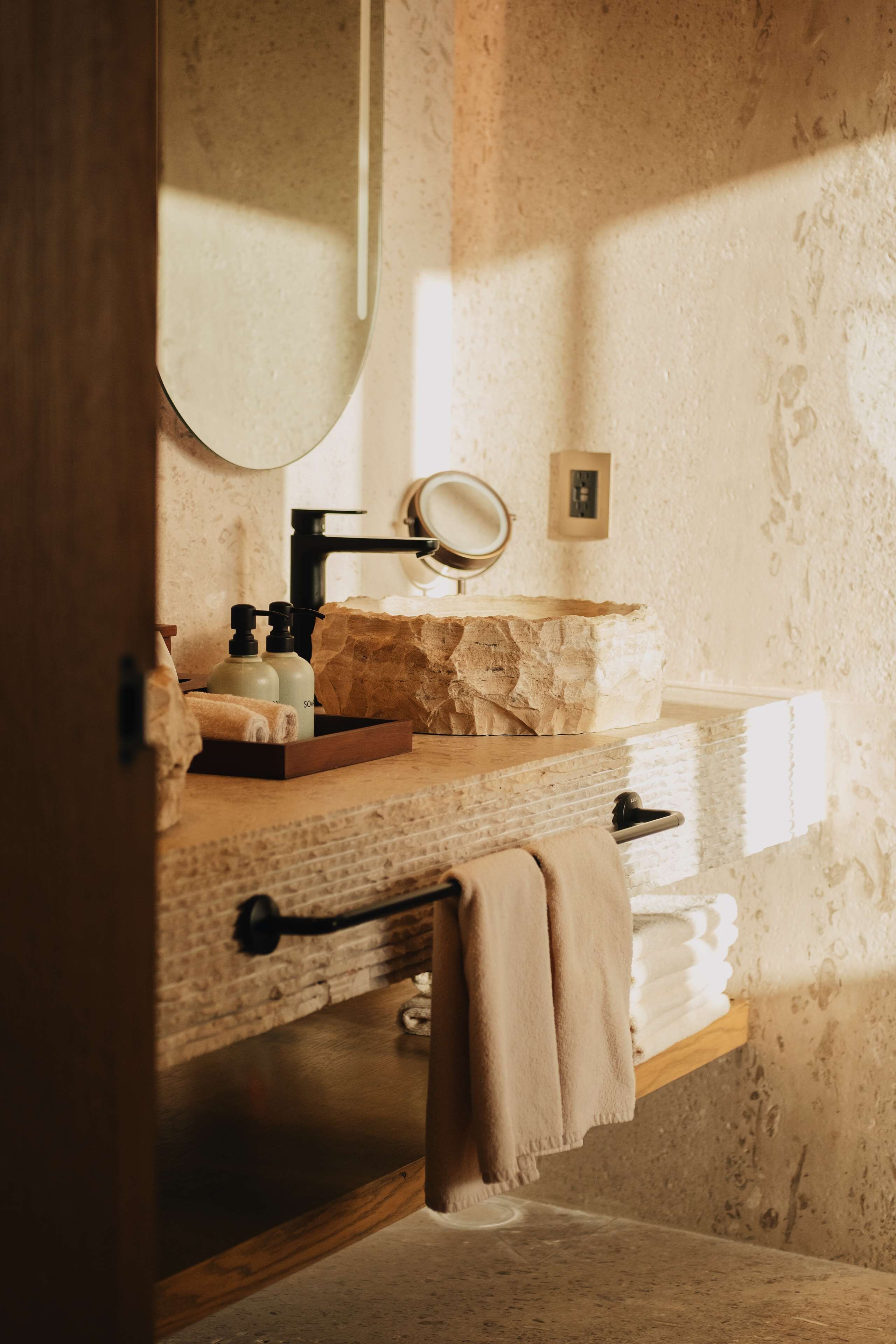 Une salle de bain avec un meuble-lavabo en bois, un miroir rond et un porte-serviettes.