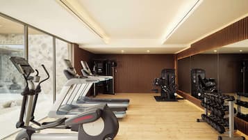 Un gimnasio con cintas de correr, elípticas y equipo de levantamiento de pesas.