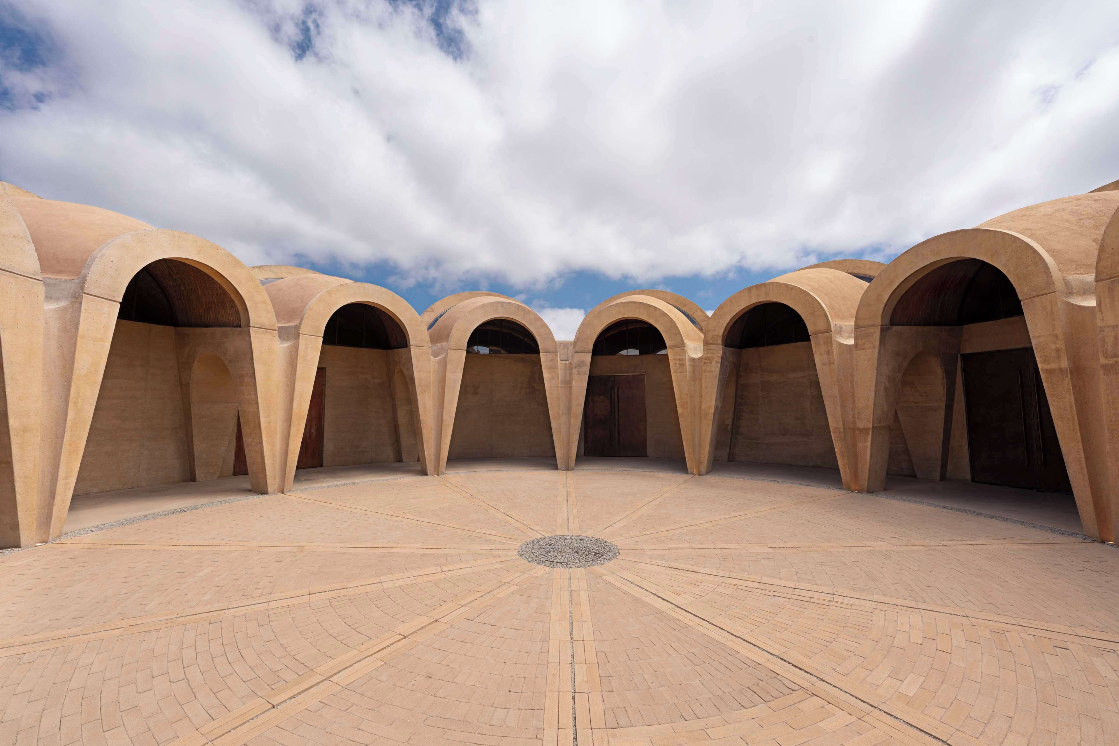 Un patio con un elemento circular central rodeado por varios arcos.
