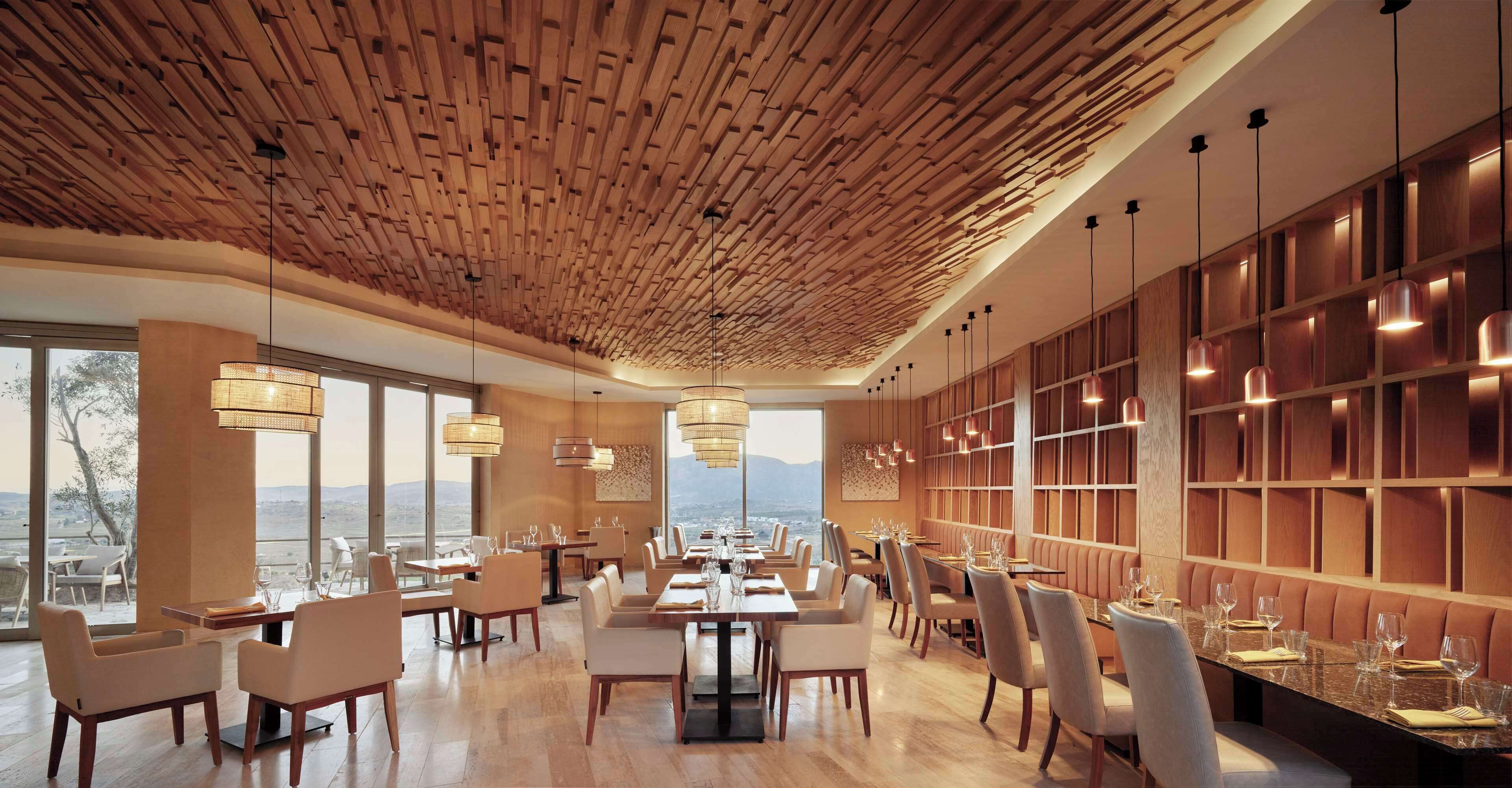 Un restaurante moderno con techo de madera, ventanas amplias y vistas al paisaje.