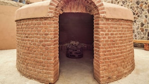 A brick oven structure with a stone wall backdrop. - Banyan Tree Veya Valle De Guadalupe (Valle de Guadalupe)
