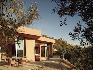Een modern huis met een terras, grote ramen en uitzicht op het omliggende landschap.