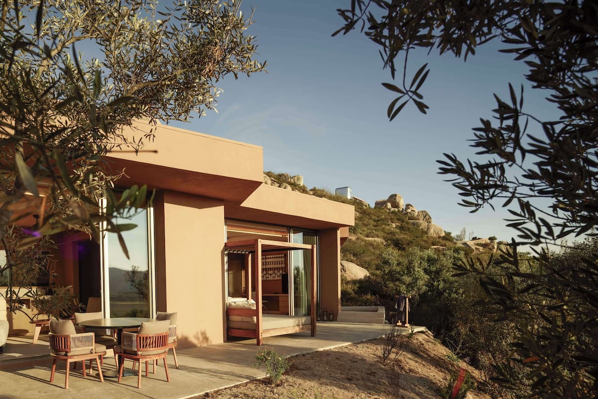 A modern house with a patio area, large windows, and a view of the surrounding landscape.