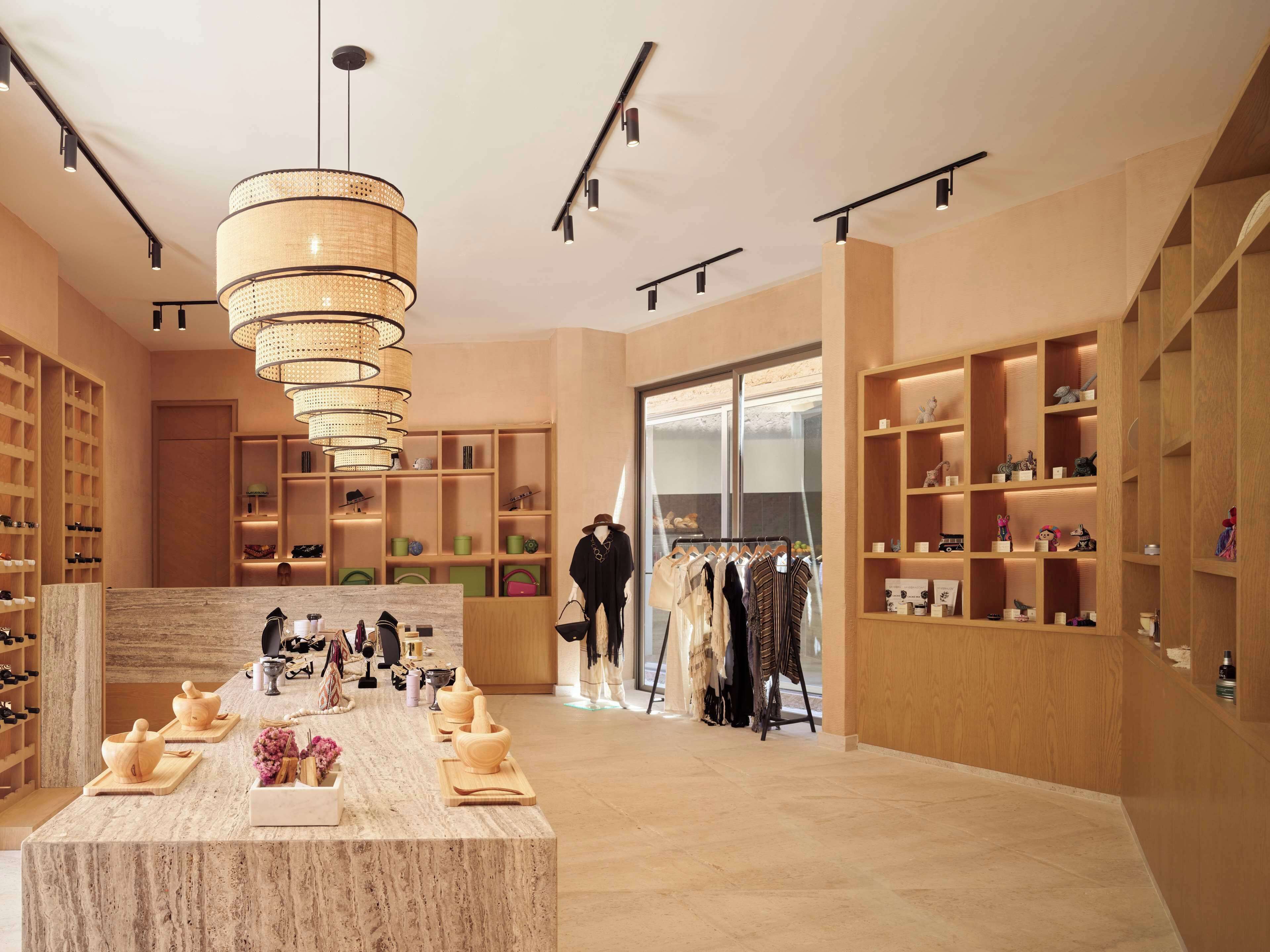 A spacious boutique hotel lobby with a marble reception desk, wooden shelving, and a clothing rack.