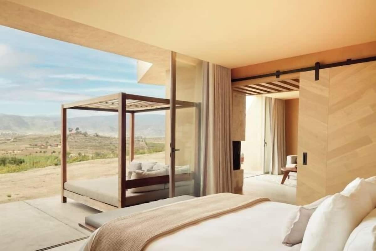 Un dormitorio con una cama grande, un separador de vidrio y vistas a un paisaje.