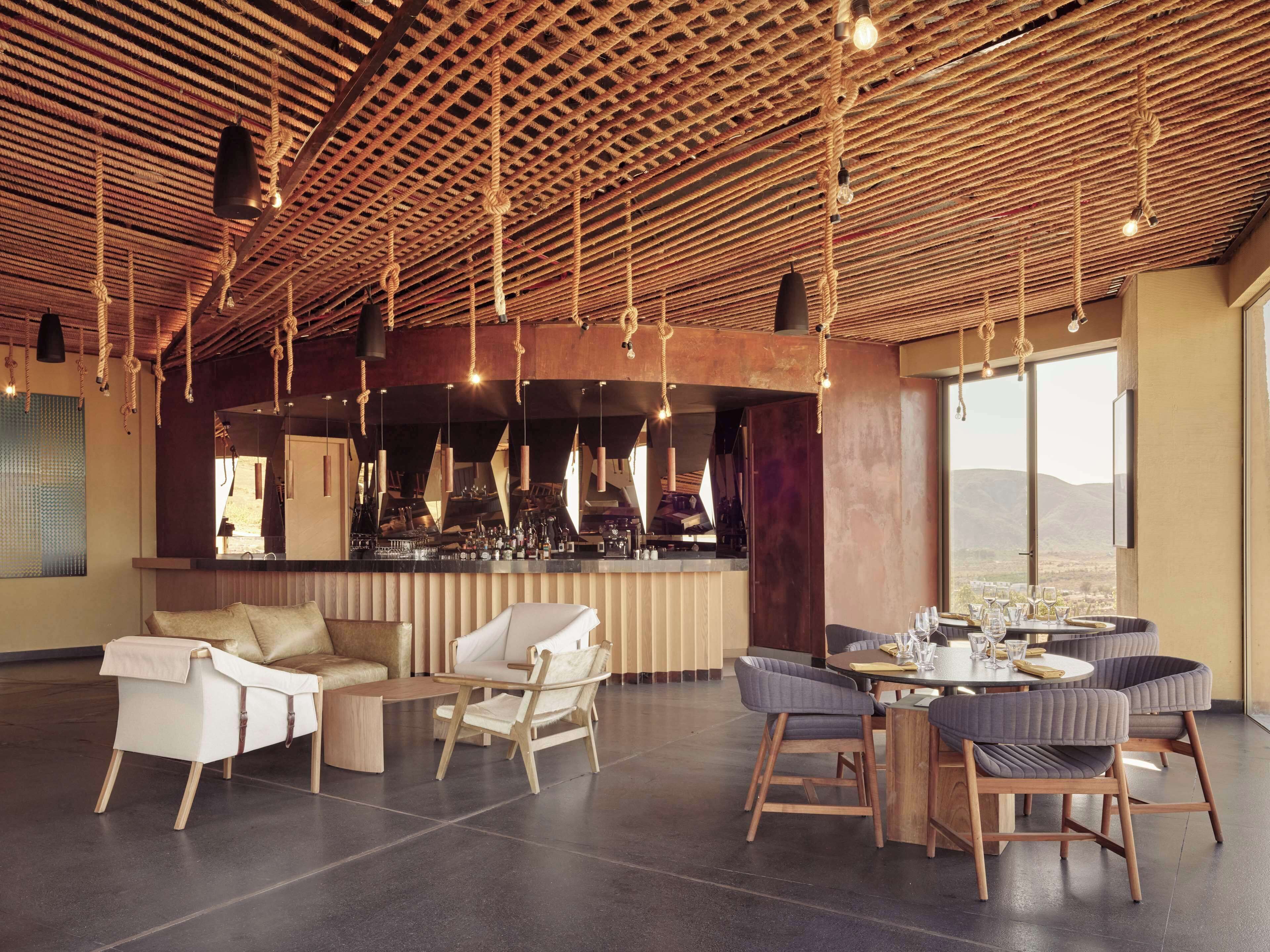 Amplia sala de estar con bar, asientos y vistas al exterior.