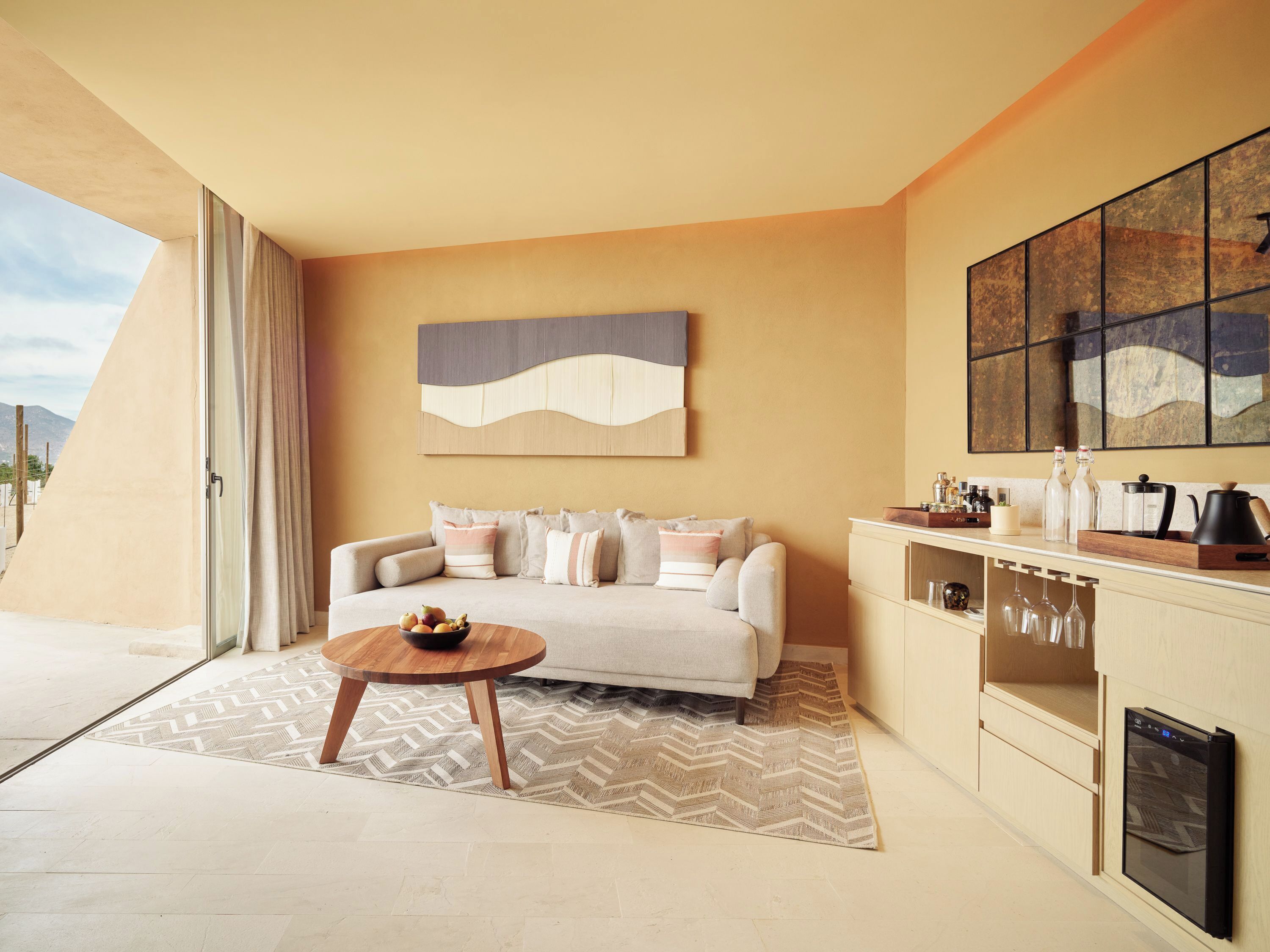 A modern living room with a sofa, coffee table, and a kitchen area with a built-in oven.