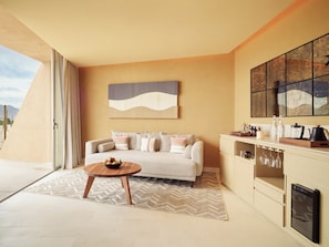 A modern living room with a sofa, coffee table, and a kitchen area with a built-in oven.