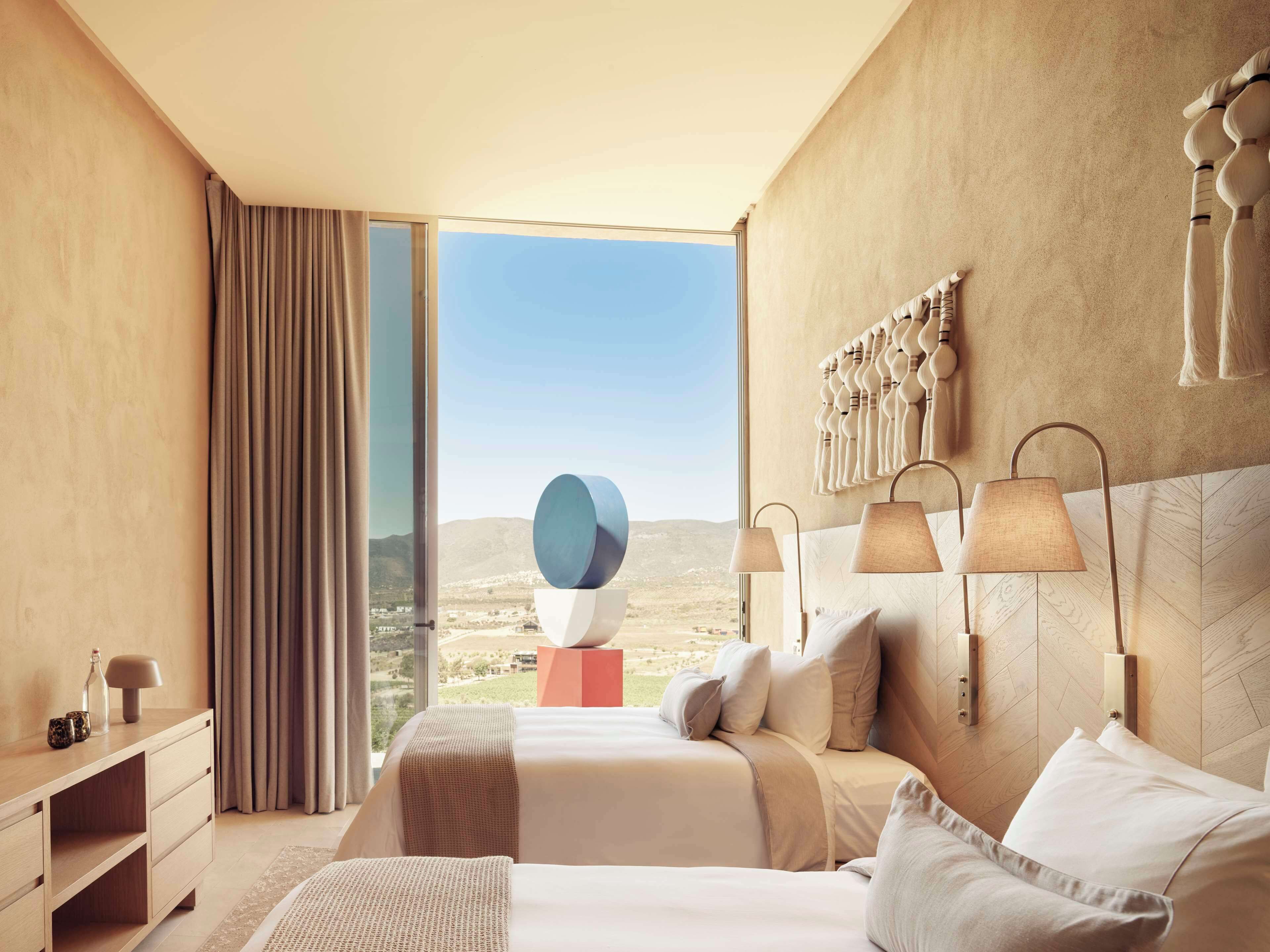 Une chambre d’hôtel moderne avec un grand lit, une table de chevet, une lampe et une vue sur le paysage.