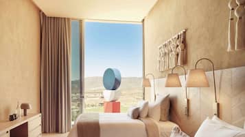 Une chambre d’hôtel moderne avec un grand lit, une table de chevet, une lampe et une vue sur le paysage.