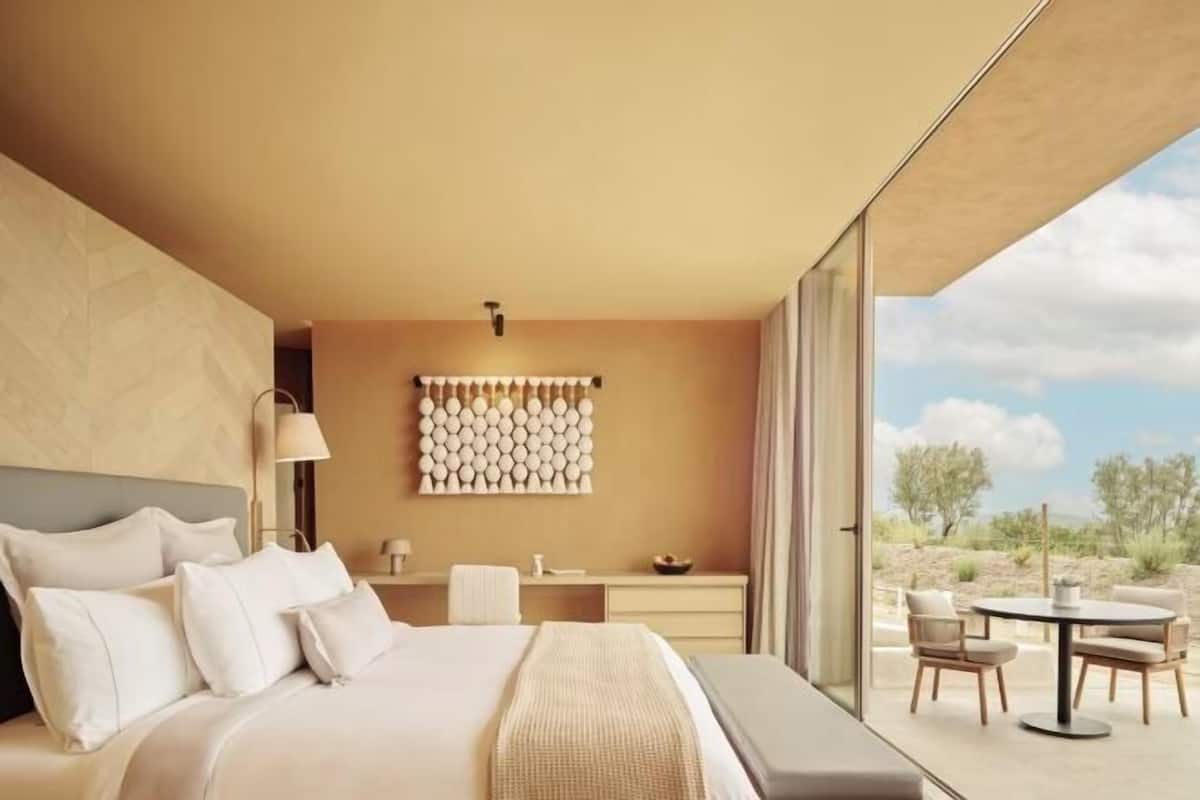 Un hotel moderno con una cama grande, un escritorio, una silla y vistas al exterior.