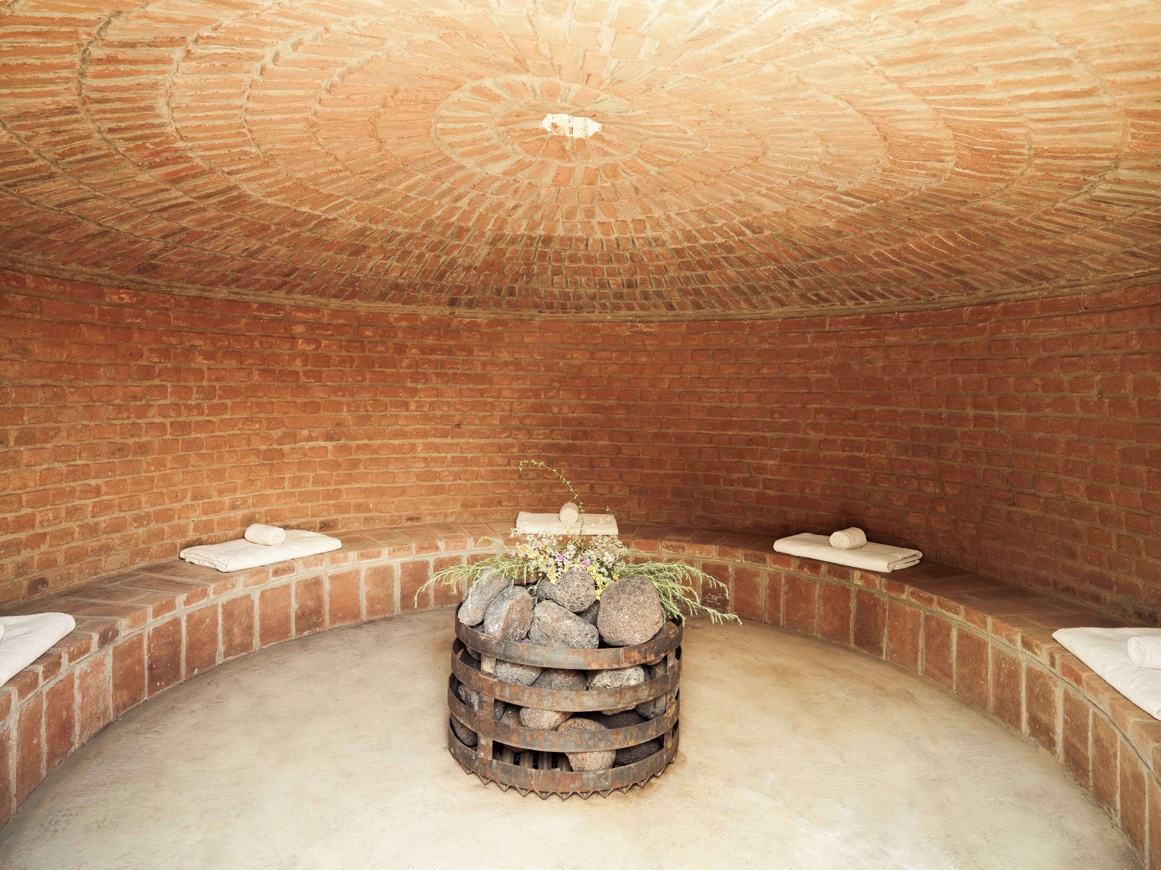 Una habitación circular con paredes de ladrillo y una chimenea central.