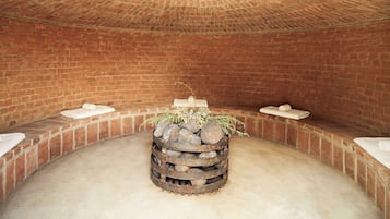 Una habitación circular con paredes de ladrillo y una chimenea central.