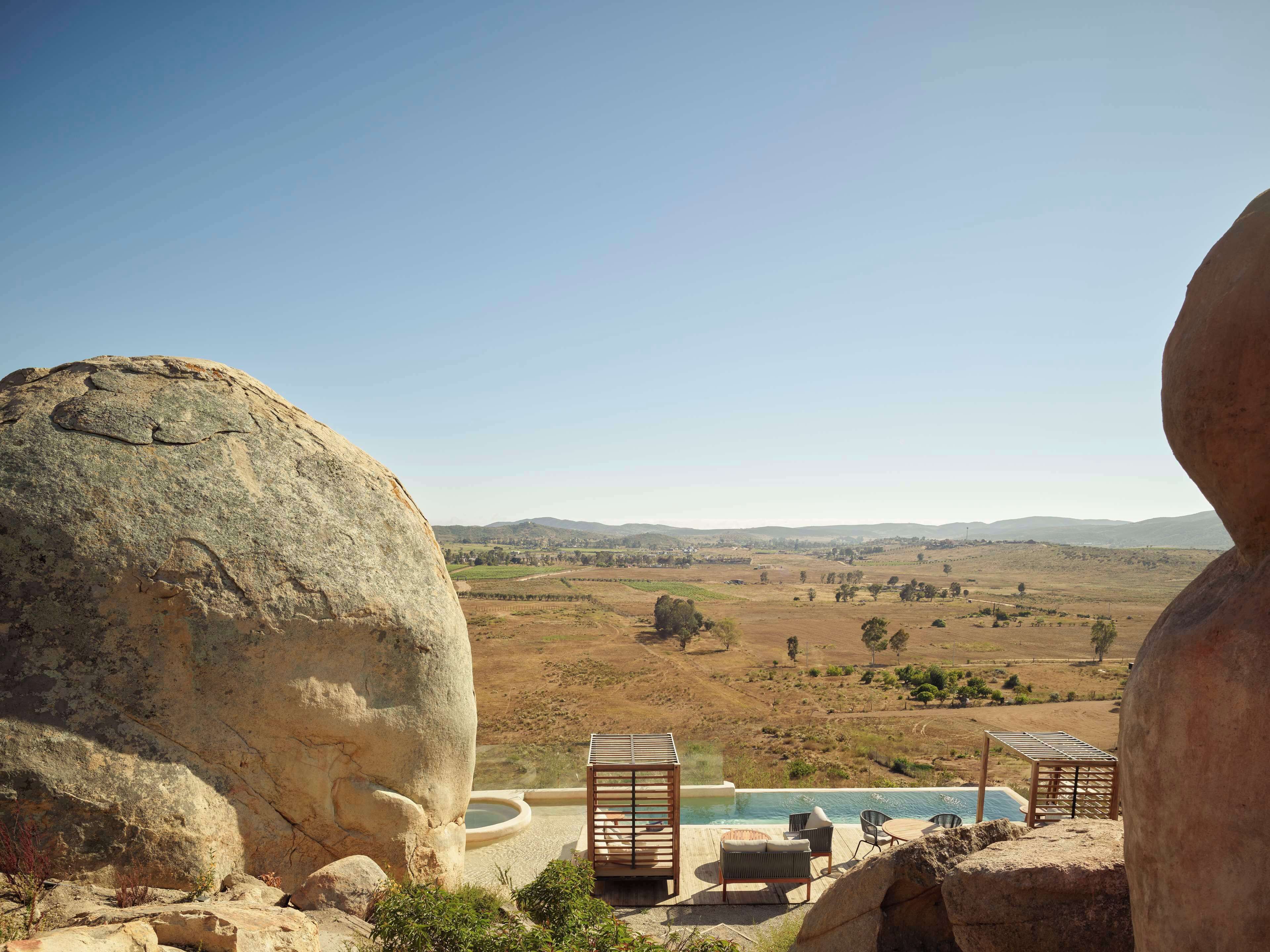 A pool area with lounge chairs and a view of a hilly landscape.
