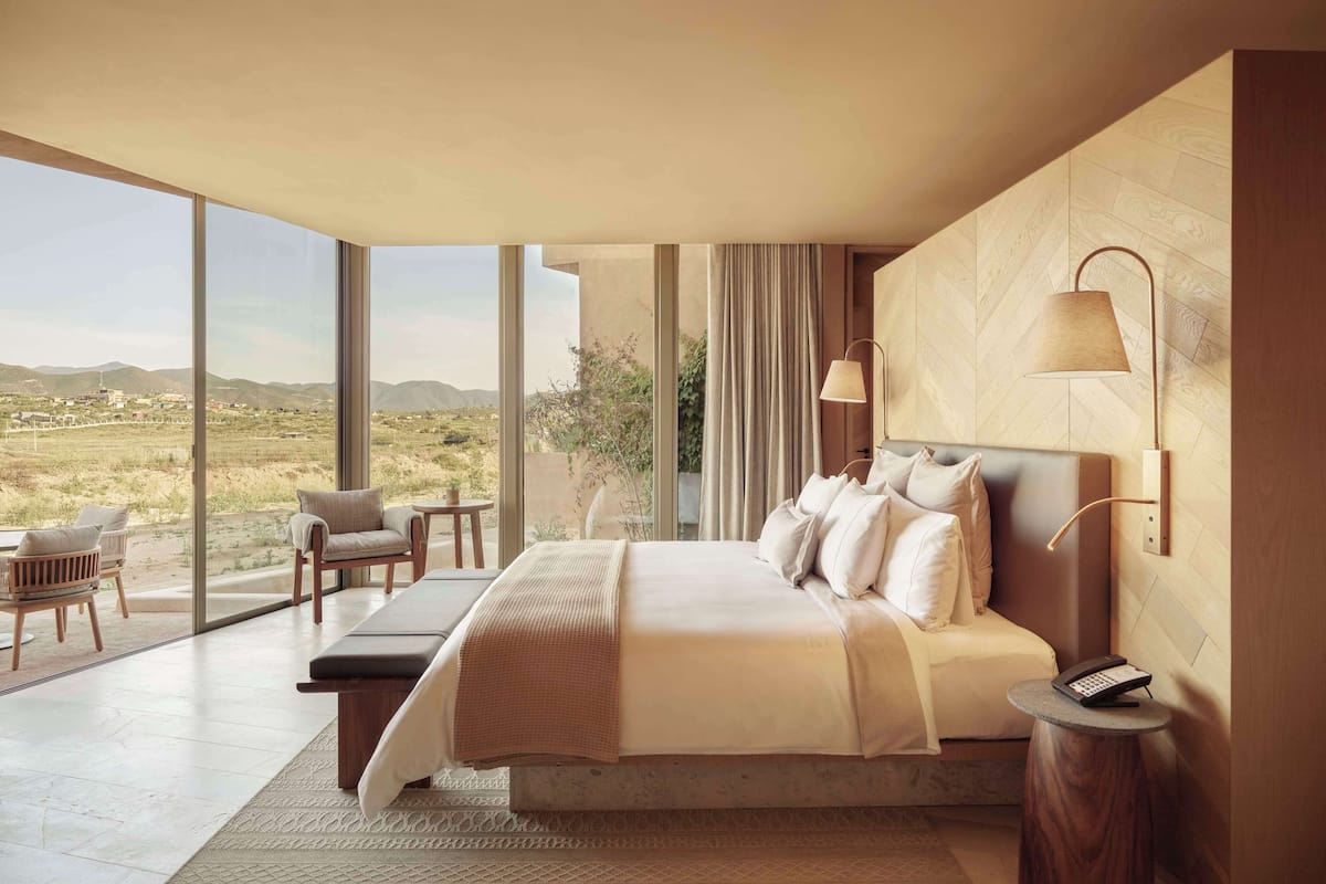 Un dormitorio moderno con una cama grande, un escritorio y vistas al campo.