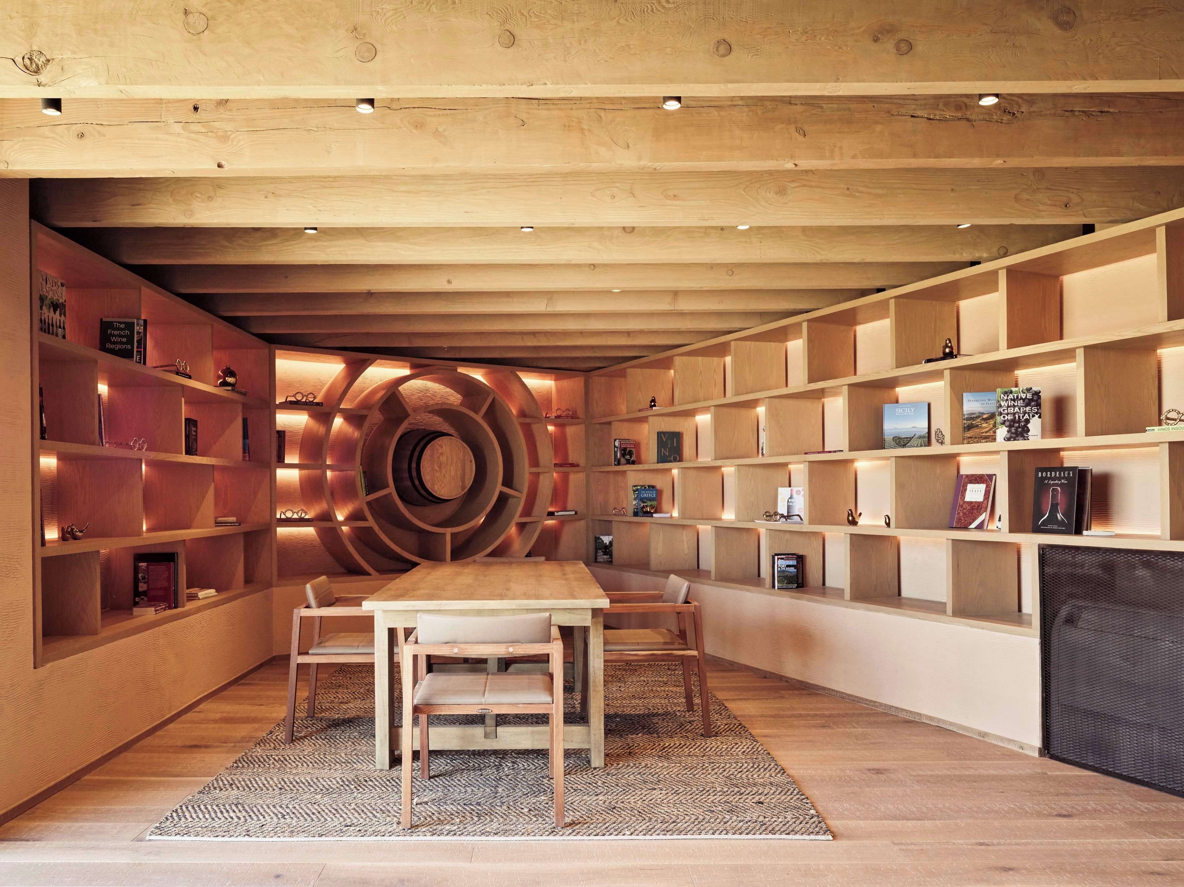 Un interior moderno con una estantería espiral central, piso de madera y un comedor con sillas.