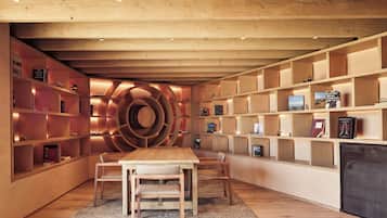 Un interior moderno con una estantería espiral central, piso de madera y un comedor con sillas.