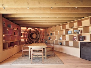 Un interior modern amb una biblioteca espiral central, terres de fusta i una zona de menjador amb cadires.