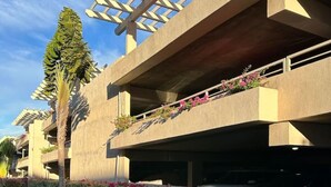 Un edificio moderno con techo plano, zona de estacionamiento cubierta y césped bien cuidado.