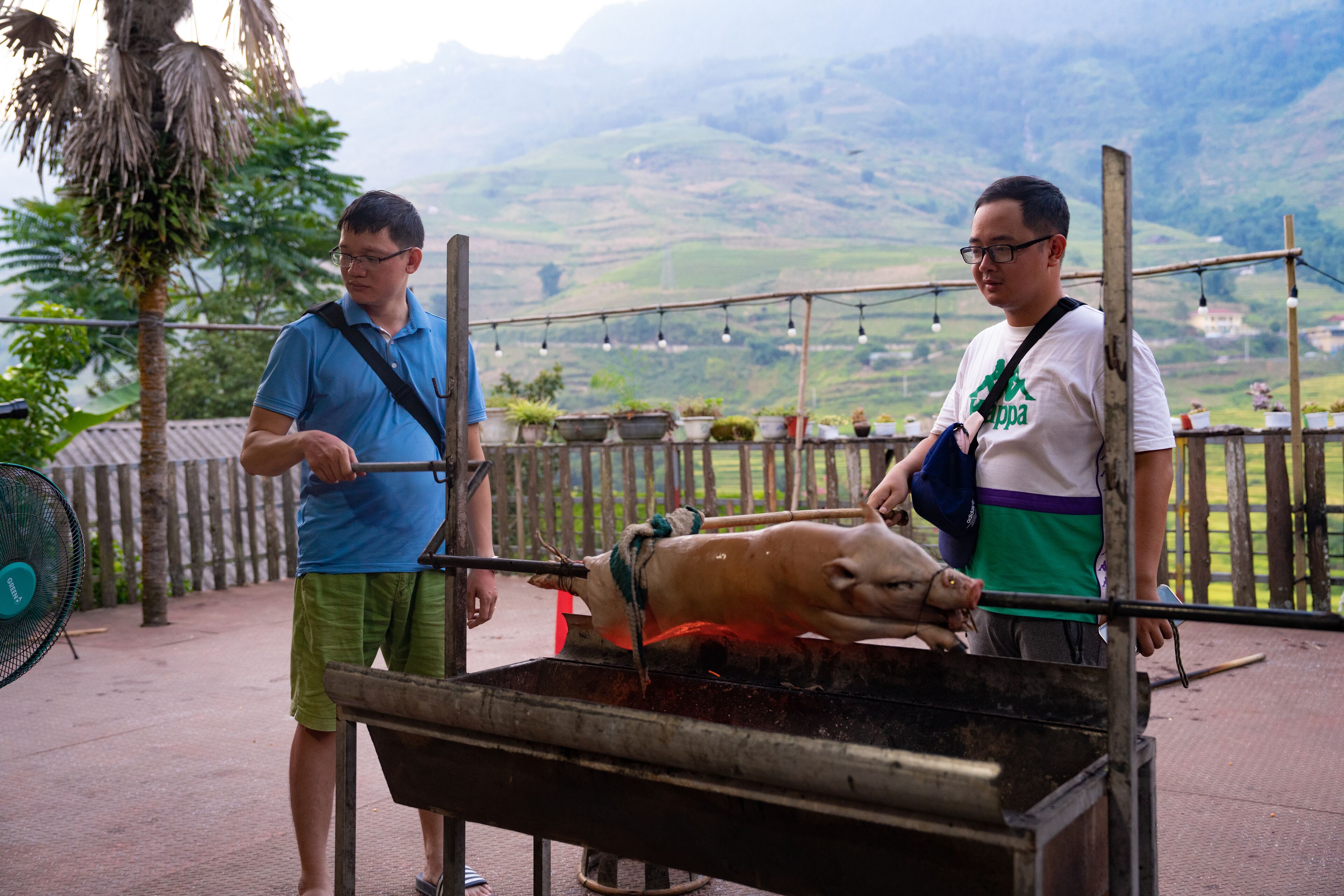 Two men standing by a large outdoor grill with a pig being cooked.