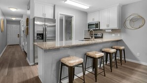 Una cucina moderna con elettrodomestici in acciaio inossidabile, un piano di lavoro in granito e sgabelli da bar.